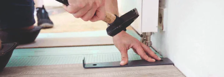 Person befestigt Metallschiene mit Hammer